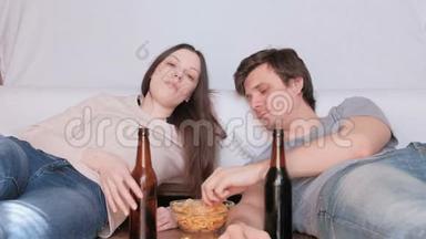 几个年轻的男人和女人吃薯片喝啤酒看电视。
